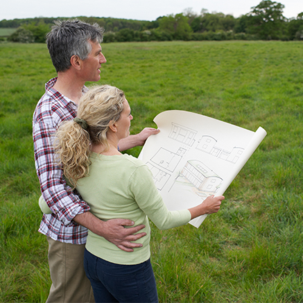 couple looking at house plans in a field